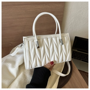 Detail of white pleated handbag featuring faux leather texture and silver metal hardware