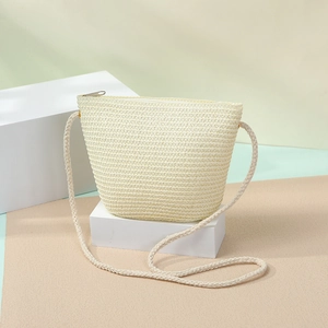 Detailed straw weave texture of the beige woven crossbody bag on minimalist geometric props