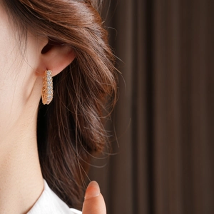 Gros plan de boucles d'oreilles dorées avec pavé de zircones blanches sur un modèle