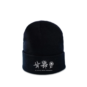 Close-up of white flower embroidery and kindness slogan on a black knitted beanie