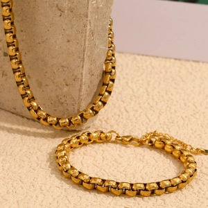 Detail of 18K gold plated round box chain necklace and bracelet set on stone base