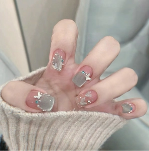 Close-up of cat eye gradient press-on nails with 3D metal butterflies and rhinestones