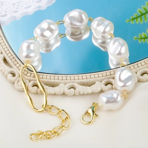 Detail of baroque pearl bracelet with gold lobster clasp on a reflective mirror base