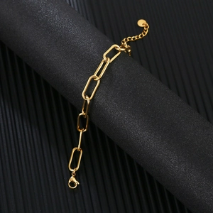 Detail of gold paperclip chain bracelet with lobster clasp on a display stand
