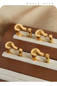 Macro view of four gold question mark rings in a velvet wooden jewelry display box