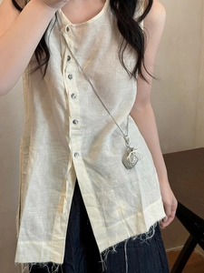 Close-up of woven heart pendant on a silver chain over a cream linen vest top