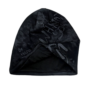 Close-up of black knitted beanie featuring decorative Be Happy and Why Not art lettering