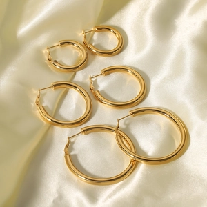 Three pairs of vintage 18K gold plated stainless steel hoop earrings on silk background