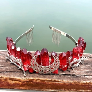 Detail of red crystal crown with silver crescent moon and branch accents on wood