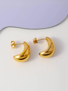 Detailed top view of gold crescent hoop earrings on a decorative purple wave background