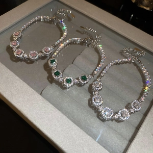 Detail of square emerald and diamond bracelets in pink, green and white on velvet tray