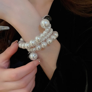 Detail of multi-layer pearl bracelet with tiered beads and black accent stones on wrist