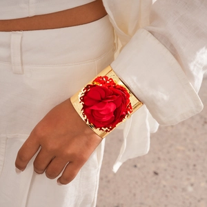 Detailed view of wide gold cuff bracelet featuring a large 3D red fabric rose decoration
