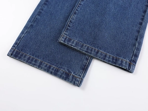 Detail of double-stitched hem on vintage wash wide-leg denim jeans in dark blue