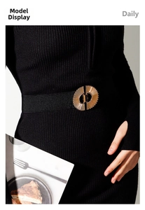 Detail of elegant black elastic waist belt with textured gold circular alloy buckle on dress