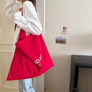 Detail of red canvas tote bag with Sunday print showing capacity and shoulder strap