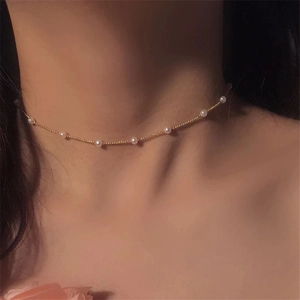 Elegant vintage minimalist gold pearl choker necklace worn on a female collarbone
