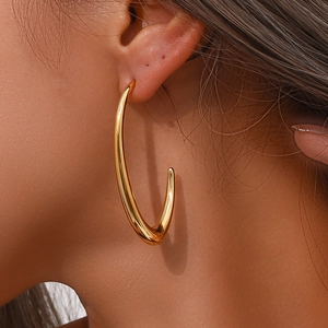 Detailed close-up of large polished gold V-shaped hoop earrings worn by a model