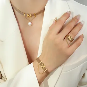 Gold plated M-letter pearl necklace and mesh bracelet jewelry set on a female model