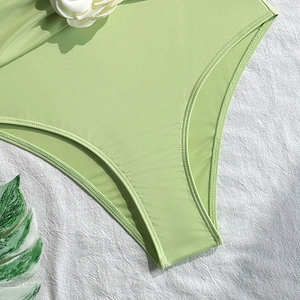 Detail of light green bikini fabric with double-needle stitching and floral accents