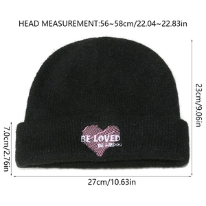 Detalle de corazón rosa bordado y texto en gorro de punto negro mostrando las costuras