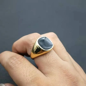 Close-up of a gold-plated signet ring with a smooth black inlay worn on a hand