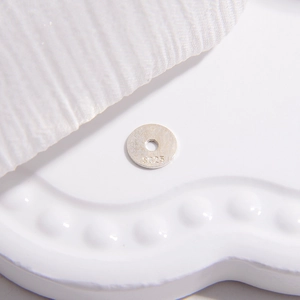 Macro view of S925 sterling silver flat round spacer beads on a white tray