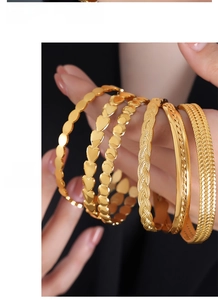 Detail of 5-piece gold titanium steel bracelets set featuring heart and woven designs