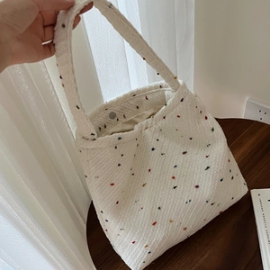 Dettaglio della borsa tote in tessuto crema con macchie colorate e tracolla minimal