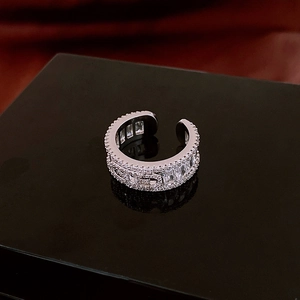 Detailed view of silver open ring with zircon stones on a dark reflective pedestal