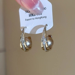 Close-up of champagne pearl earrings with zircon inlay in a C-shaped silver frame