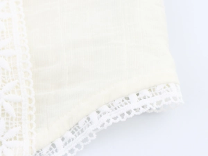 Close-up of beige cotton fabric with intricate white lace trim and pleated texture