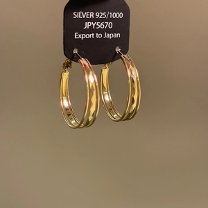 Detailed view of gold plated 925 silver hoop earrings with diamond-cut texture pattern