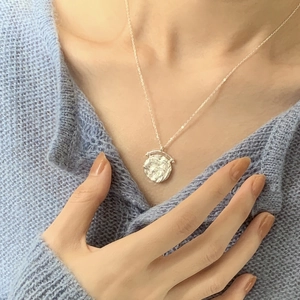 Dettaglio di una collana in argento sterling 925 con pendente a moneta testurizzata