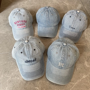 Five assorted washed denim baseball caps with vintage embroidery on marble background