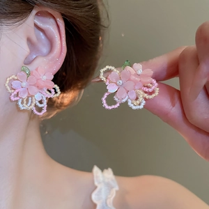 Détail de boucles d'oreilles fleuries perlées avec pétales en résine rose et perle