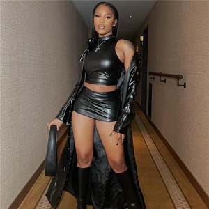 Detail of black PU leather set featuring cropped top and high-waisted mini skirt with coat