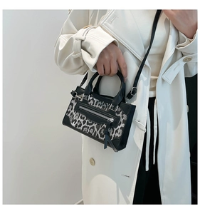 Lifestyle view of leopard print handbag with black trim and dual handles on a model