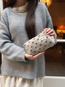 Détail de la trousse en peluche crème à pois bleus avec étiquette de marque tissée