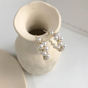 Boucles d'oreilles dorées en C avec perles et strass sur un vase en céramique