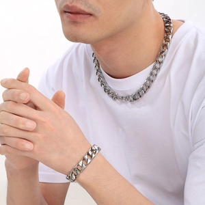 Close-up of a men's silver Cuban link chain necklace and bracelet set worn by a male model