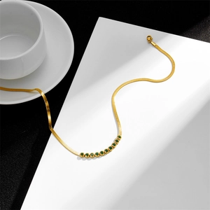 Golden flat snake chain necklace featuring inlaid round green gemstones and a lobster clasp