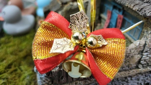 Close-up of a festive red ribbon bow with gold leaf accents and twin golden bells