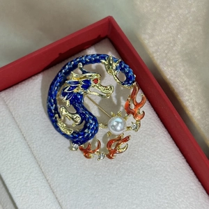 Detailed view of enamel dragon brooch with pearl and rhinestones in red gift box
