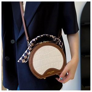 Detail of round crossbody bag with crocodile texture and plaid silk scarf handle