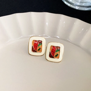 Detail of vintage square earrings with colorful floral inlay in a porcelain dish