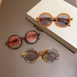 Lunettes de soleil rondes rétro en orange mat et gris sur texture de cuir élégante