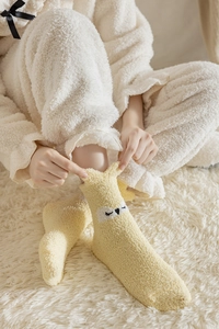 Close-up of yellow coral fleece socks with cartoon animal patterns on a plush carpet