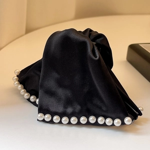 Elegant large black satin hair claw clip with white pearl edges on a cream background