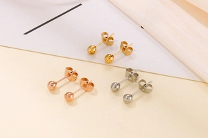 Detailed view of spherical stud earrings in gold, rose gold and silver on silk fabric